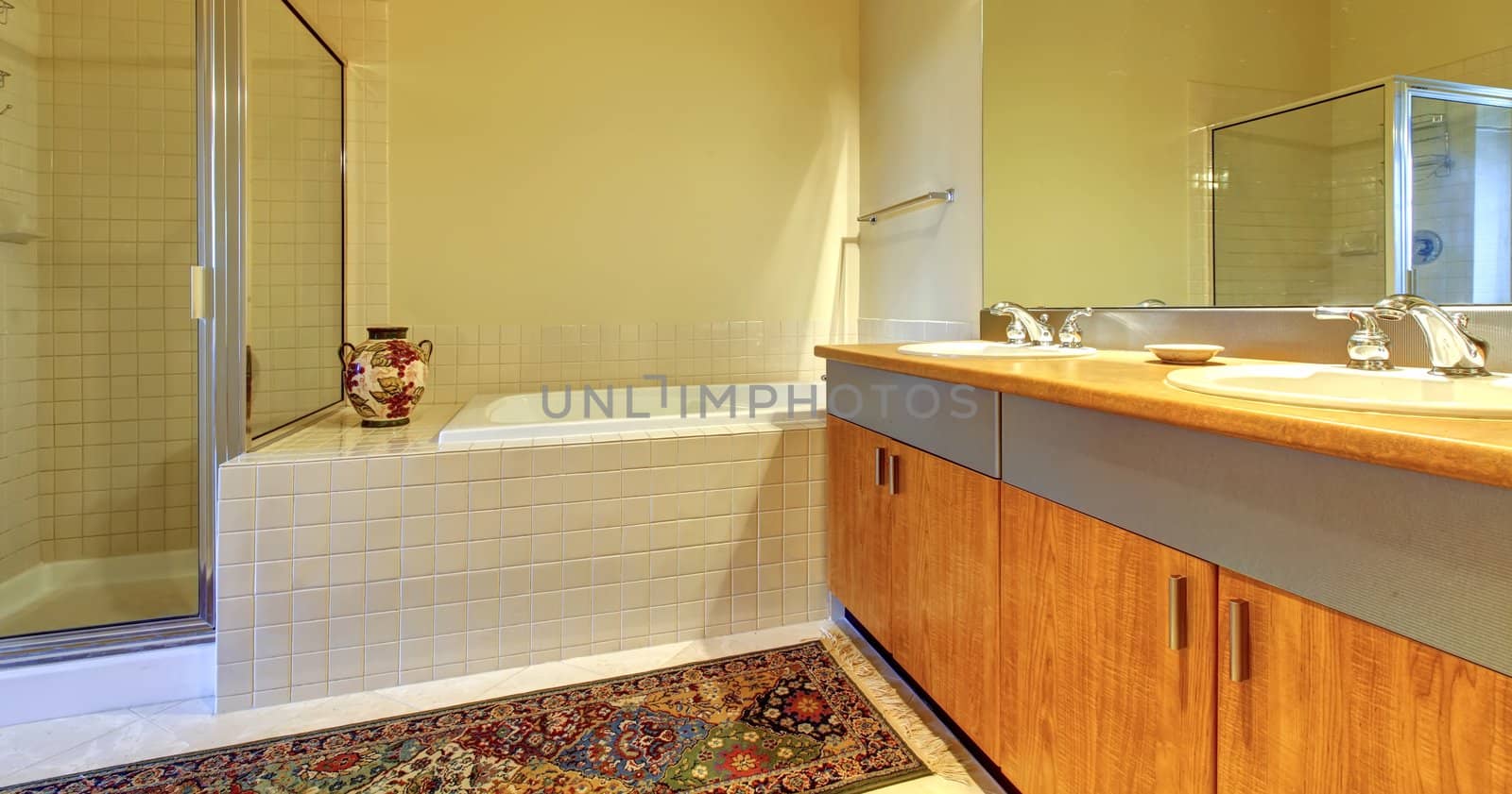 Bathroom with modern wood cabinets, tub and shower with yellow walls.