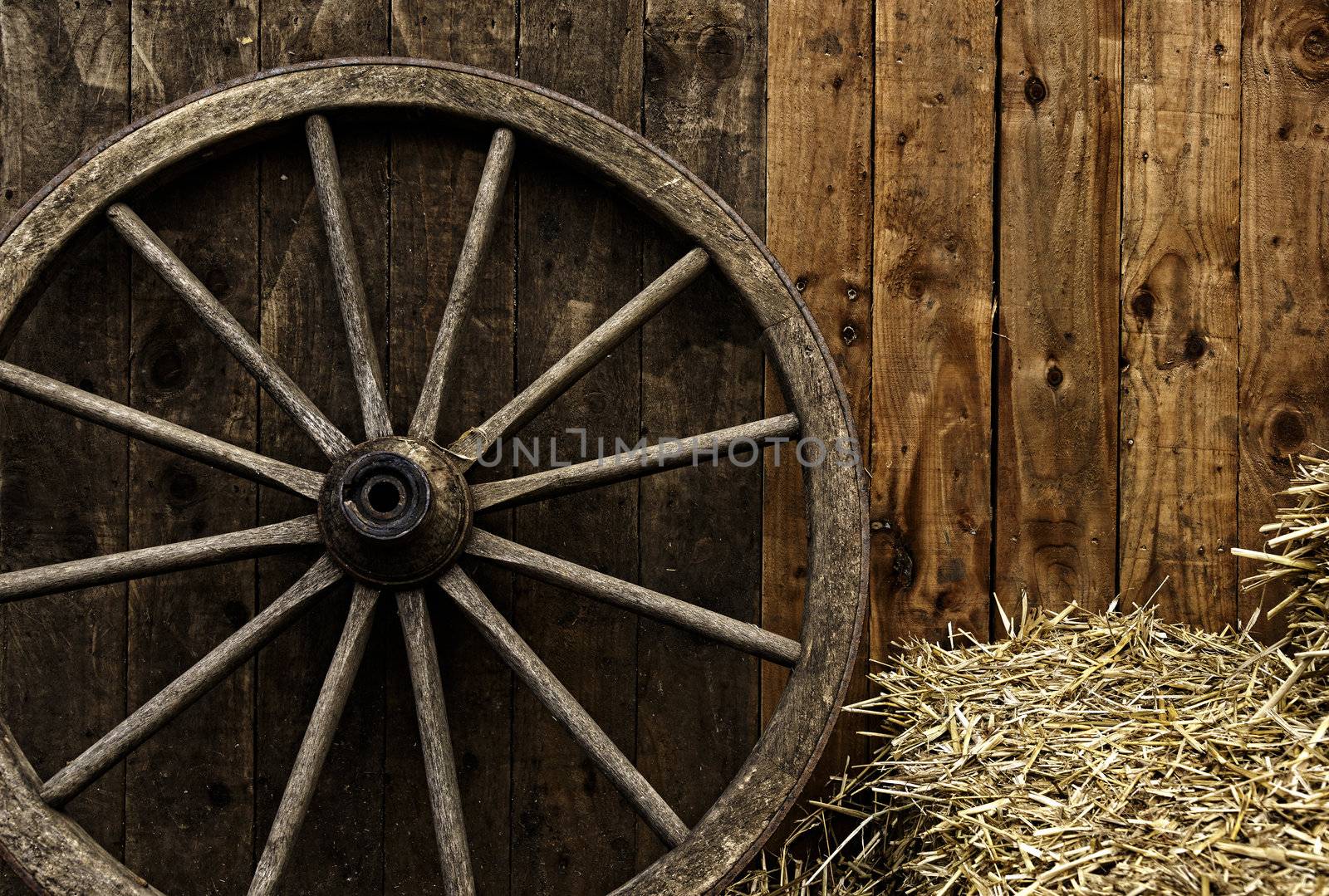 Vintage wooden carriage wheel, straw and wood background