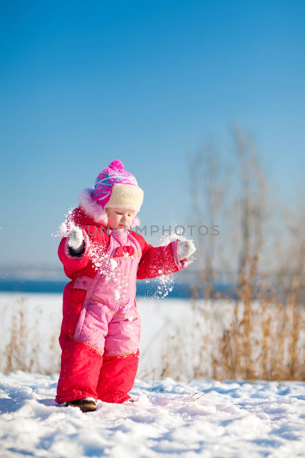 child throwing snow in winter by vsurkov