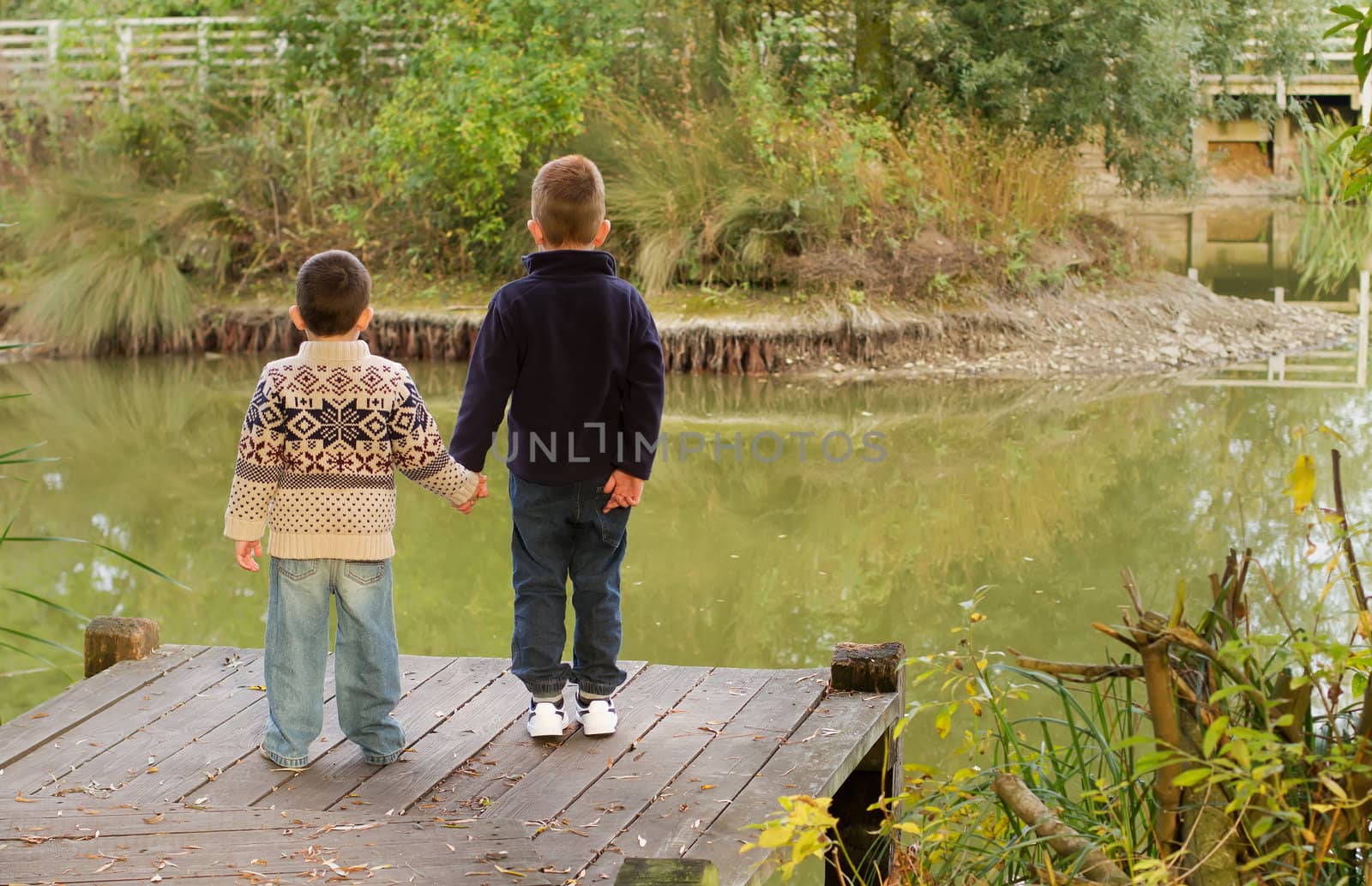 Brothers looking out across a pond in Autumn