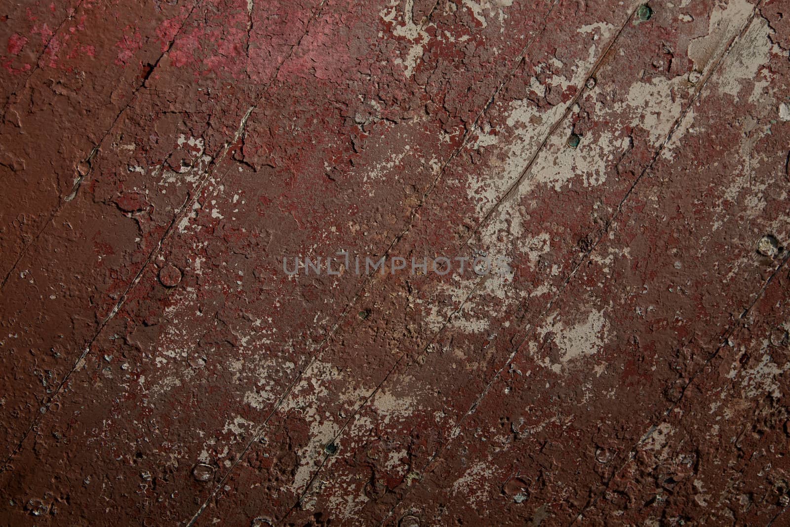 Diagonal timbers with layers, of old red flaking paint in a variety of tones.