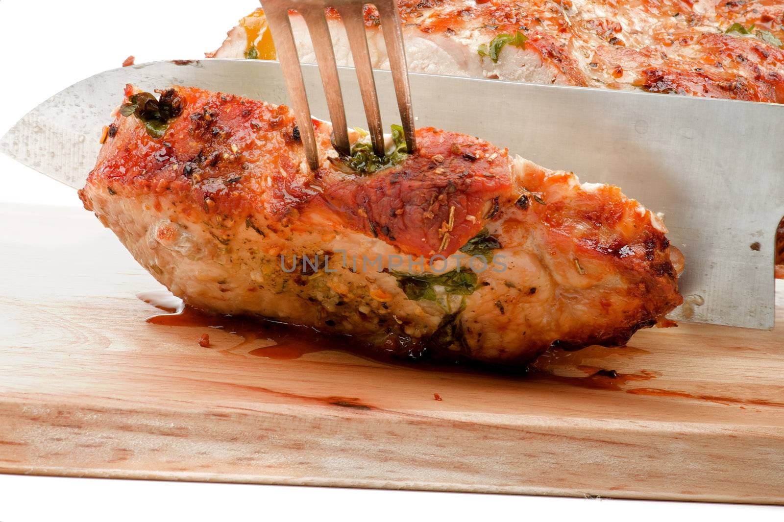 Slicing Roasted Loin Pork with Kitchen Knife and Fork closeup on Cutting Board