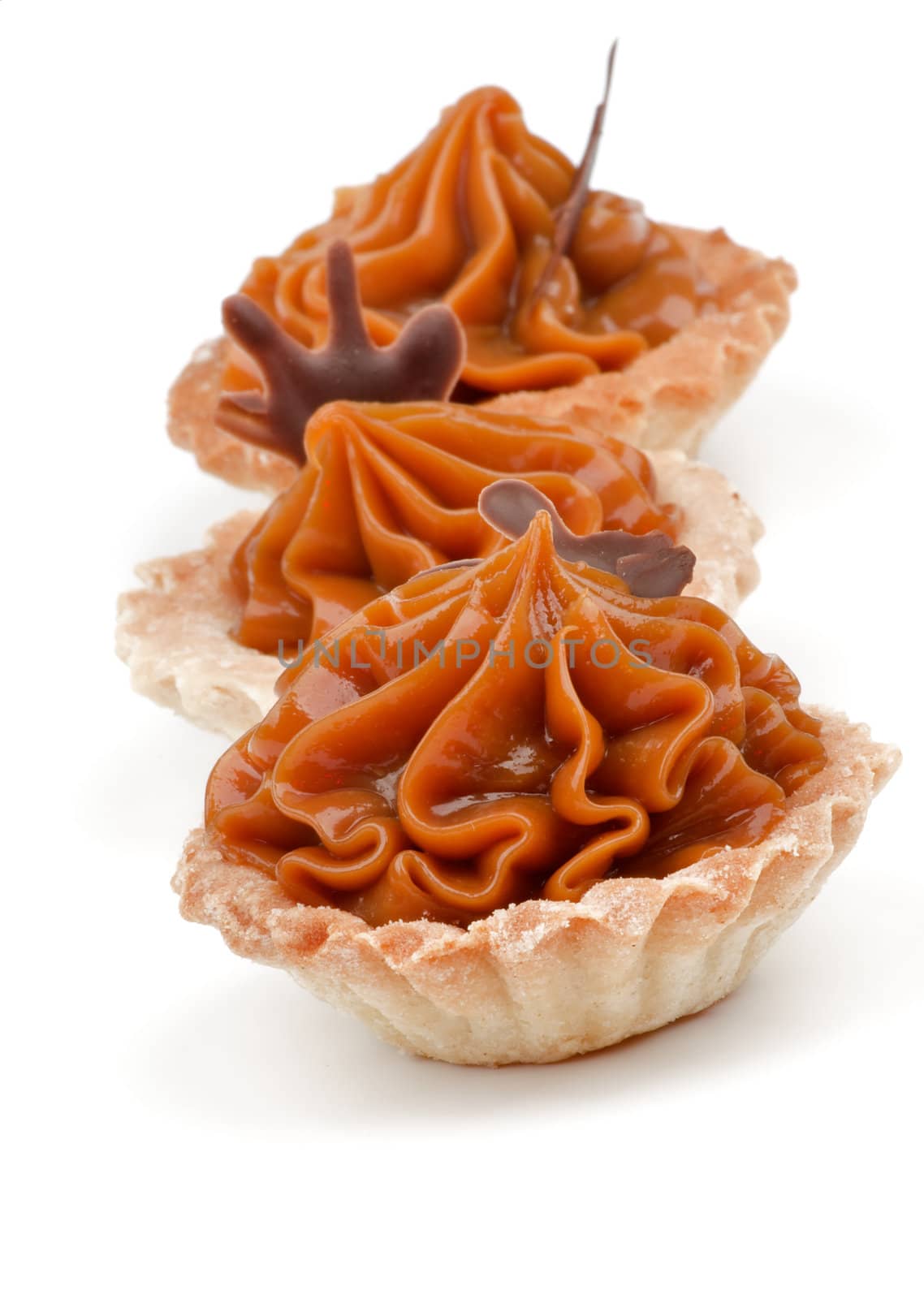 Three Delicious Little Tarts with Nougat Caramel and Chocolate Decoration in a Row isolated on white background