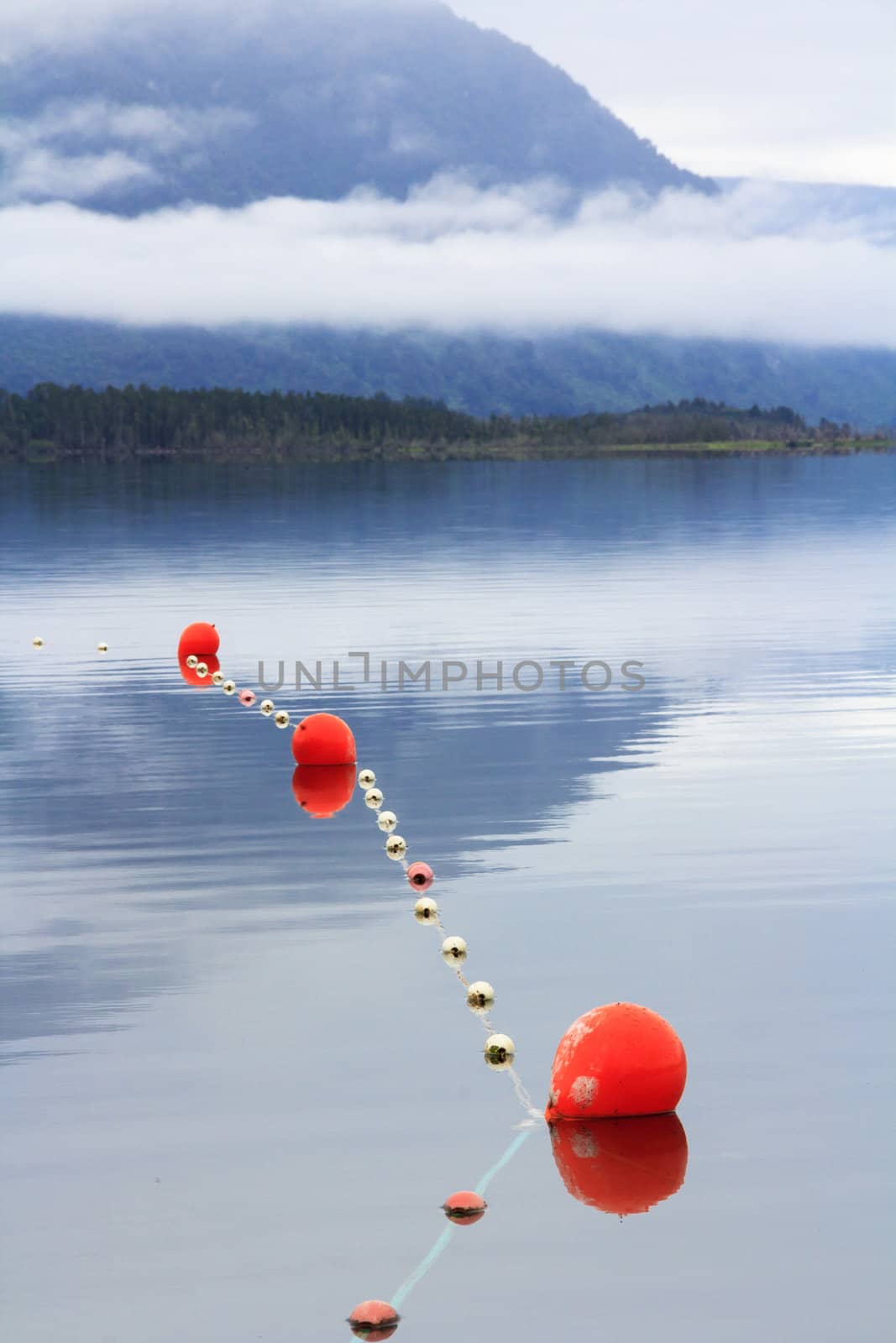 scenic mountain blue lake lanscape with the morning mist and clouds, fishing nets and orange floats