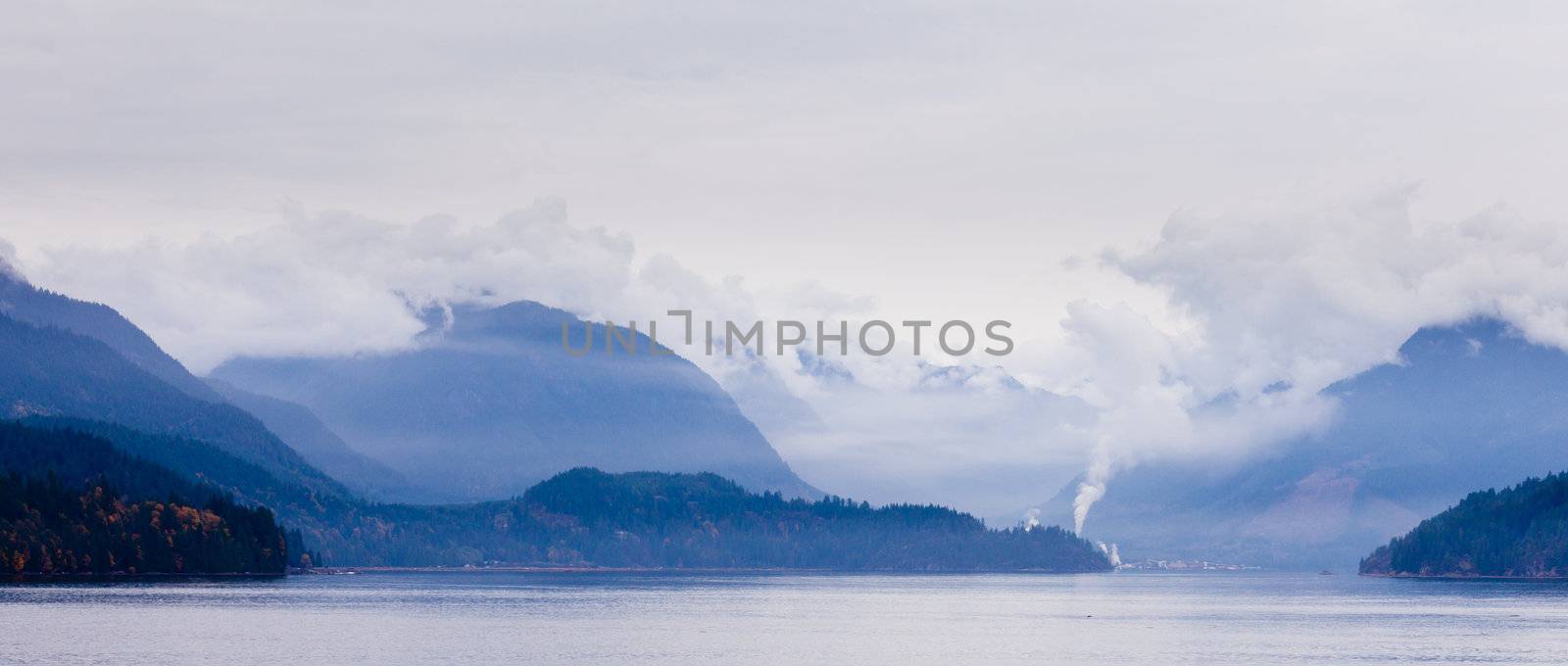 Rain clouds fog at west coast mountain ranges and fiords of Pacific Ocean in western province of beautiful British Columbia, Canada.