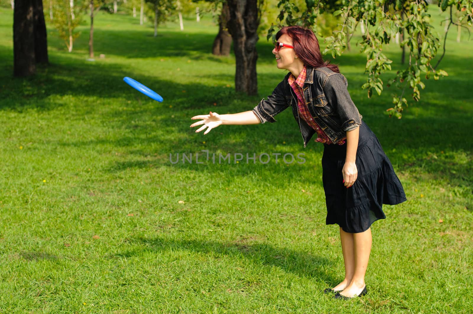 Young woman having fun with frisbee in the parkin sunny summer day.