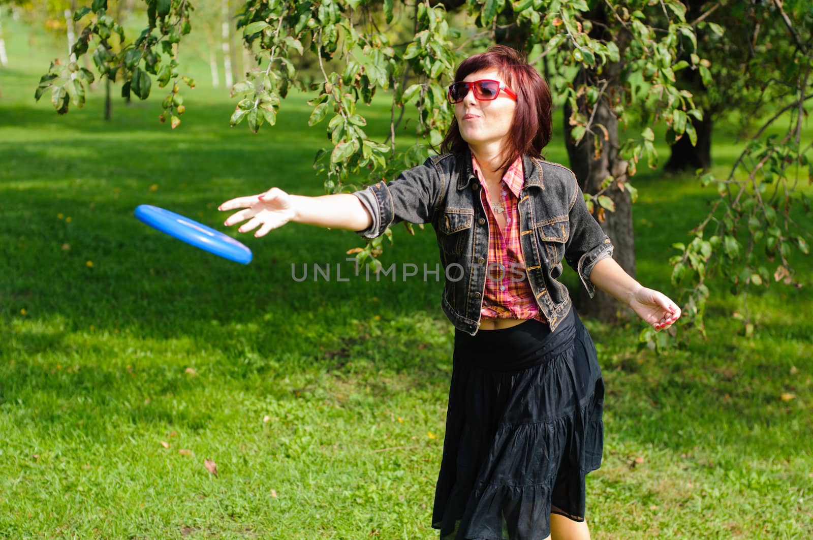 Young woman having fun with frisbee in the parkin sunny summer day.