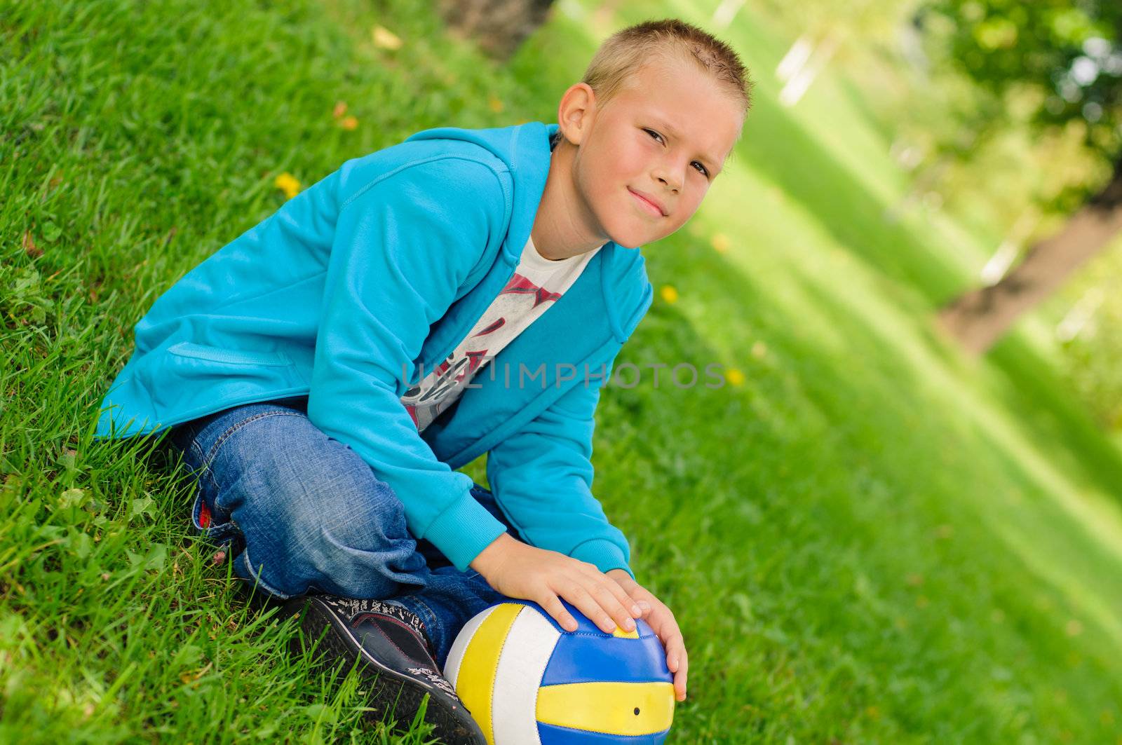 Young boy in jeans sitting on the grass