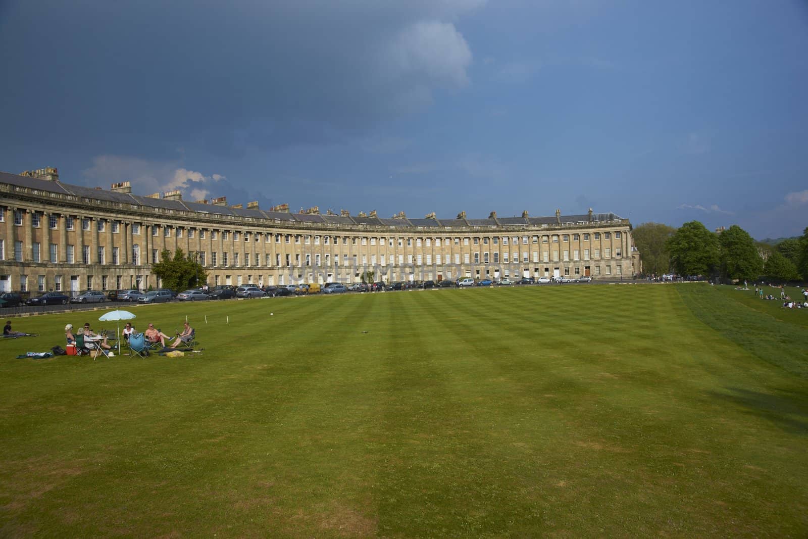 Group of people having a picnic on the grass in front of the Royal Crescent in Bath, Somerset, England.