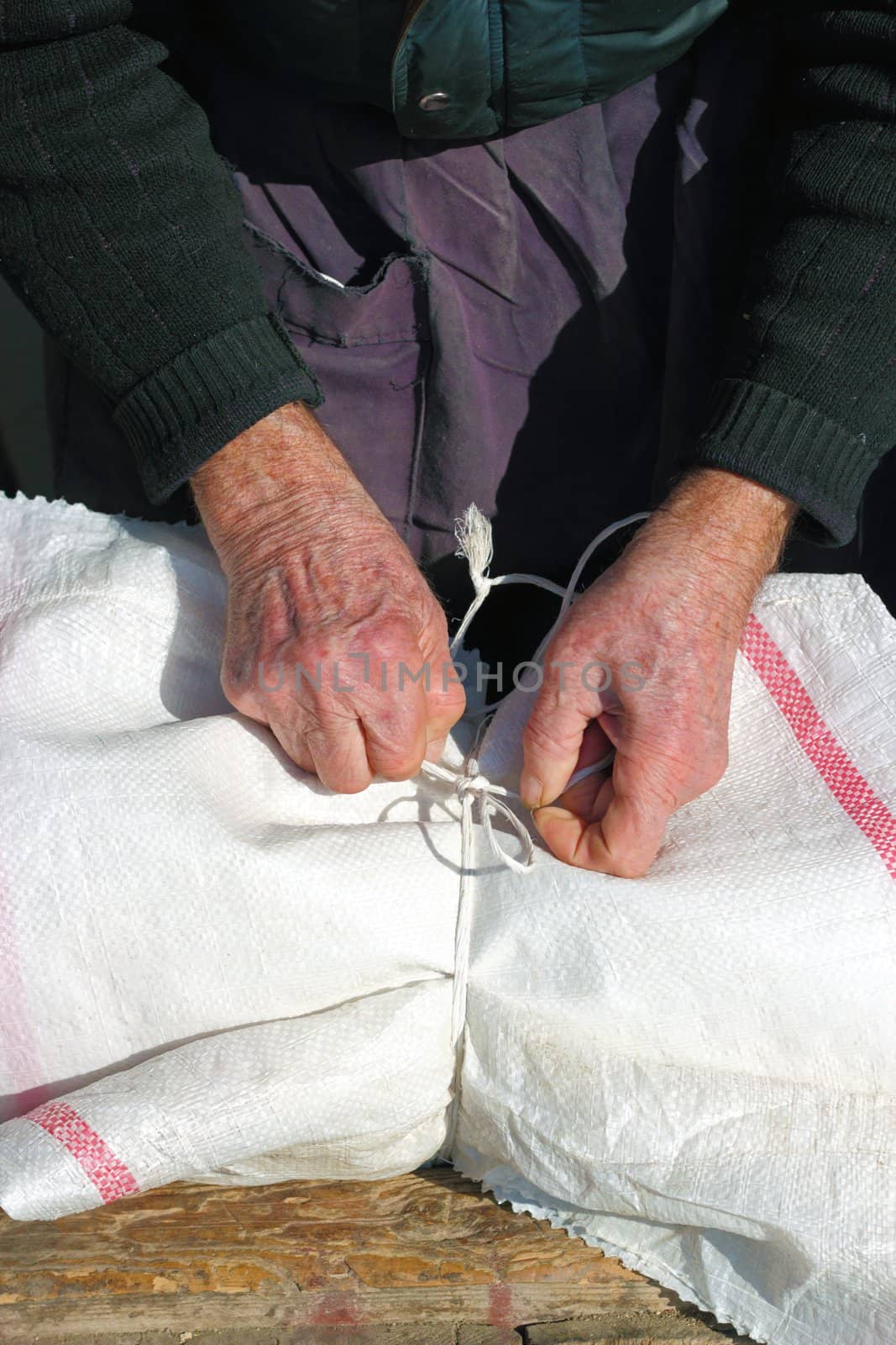 old man's hands making a knot with a string