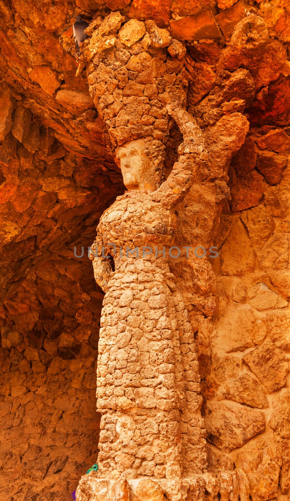 Please check again.  Photographs in Guell Park can be commerical and editiorial.
Stone Woman Colonnaded Footway Under Viaduct designed by Antoni Gaudi Guell Park, Barcelona, Catalonia, Spain.  Antonio Gaudi designed the wall with local stone, but the Stone Woman is rumored to have been created by one of Gaudi's workers.  Guell Park is a residential complex designed by Antnoi Gaudi between 1900-1914, which is now a public park.  Now a UNESCO World Heritage Site.