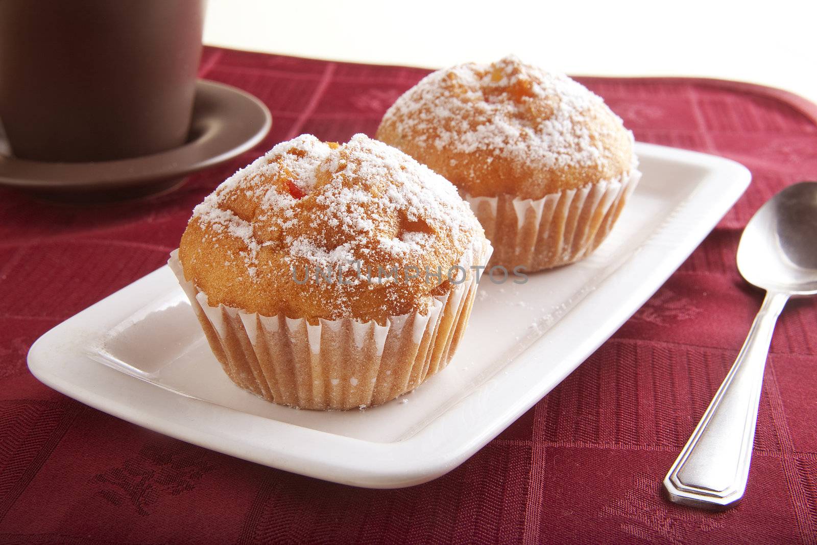 Two cakes on the white plate with cup of tea