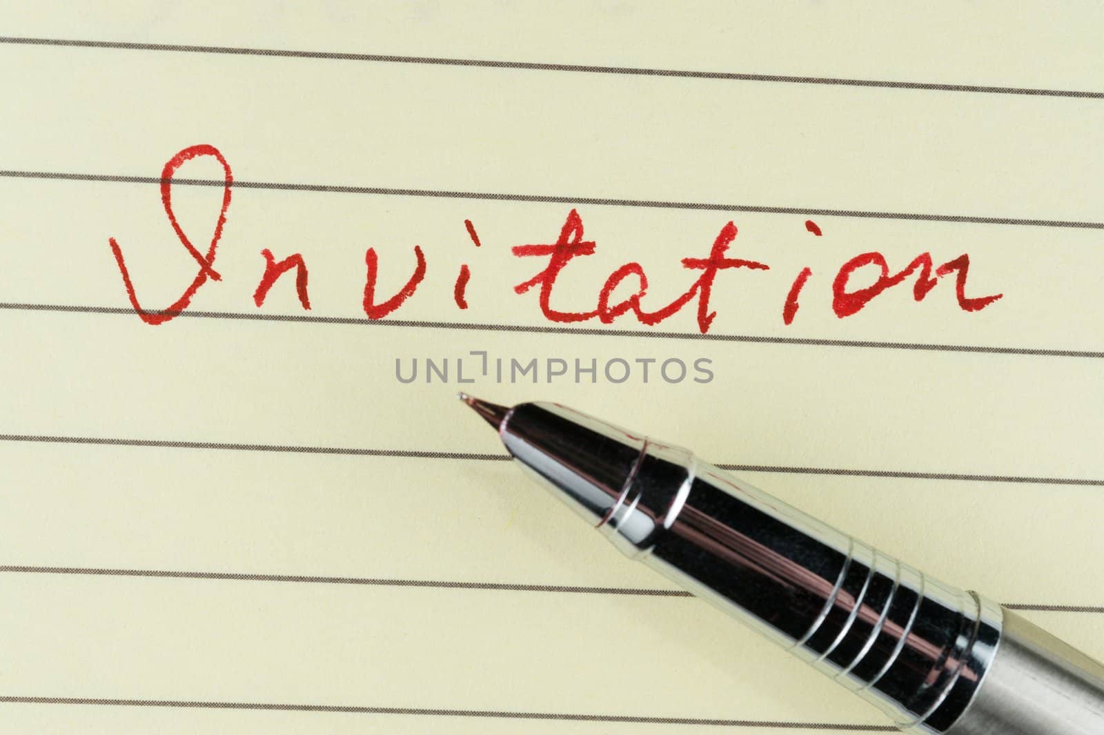 Invitation word written on lined paper with a pen on it