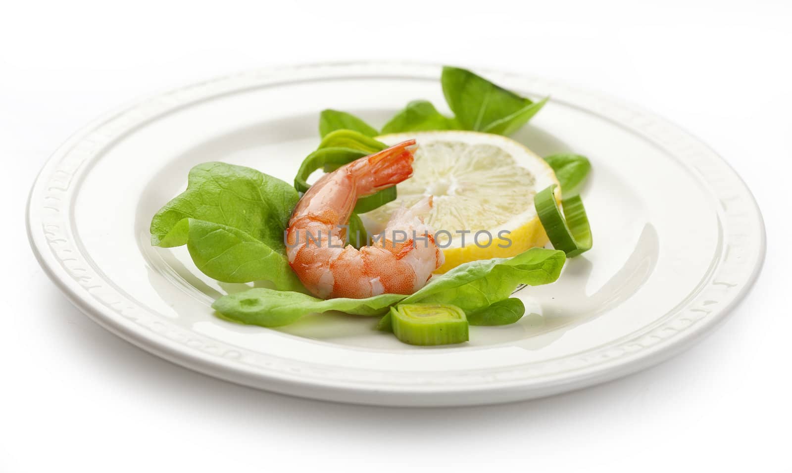 One shrimp's tail with lettuce, leek and lemon on the white plate