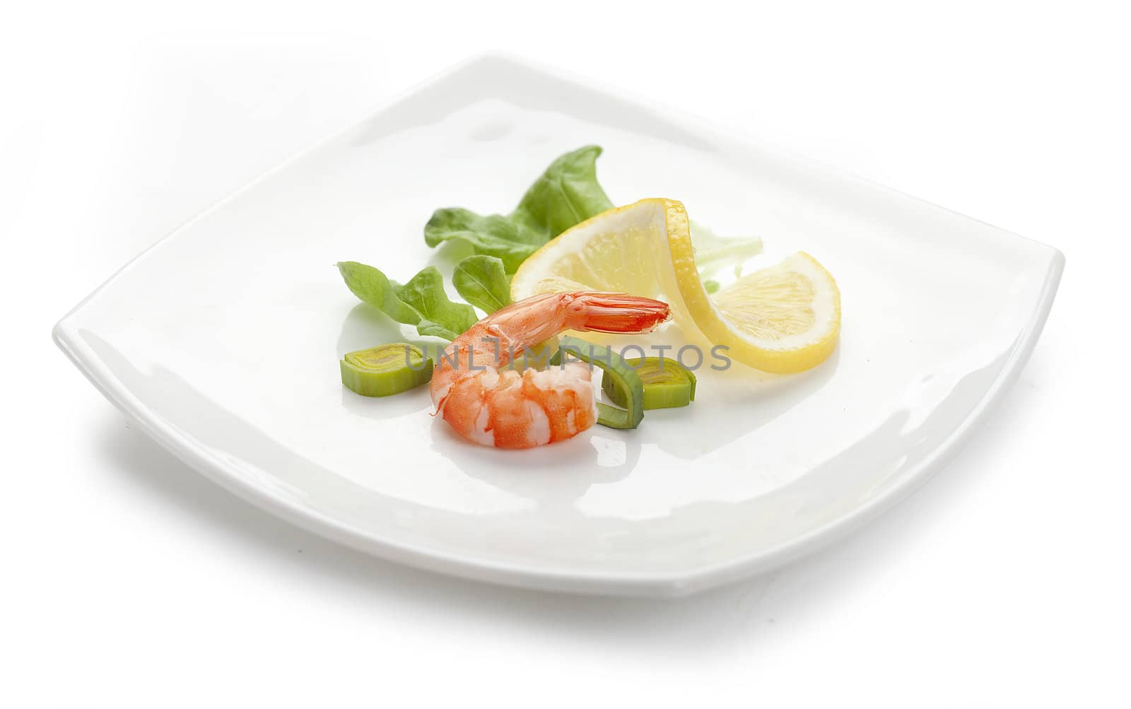 One shrimp's tail with fresh lettuce, leek and lemon on the white plate