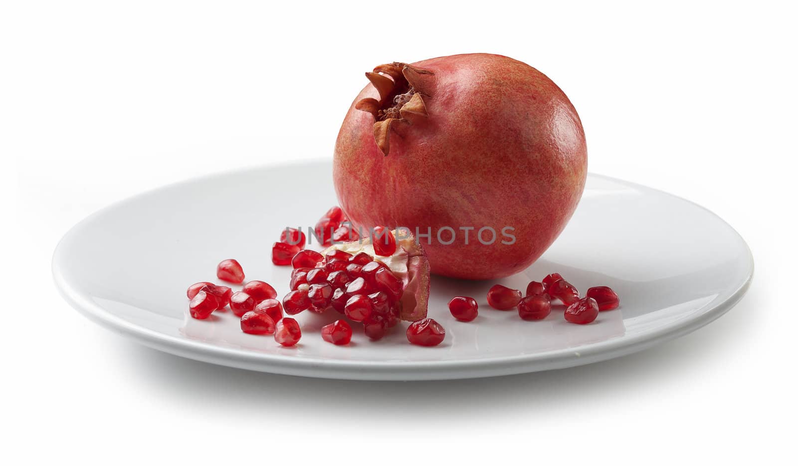 One whole red pomegranate with seeds on the white plate