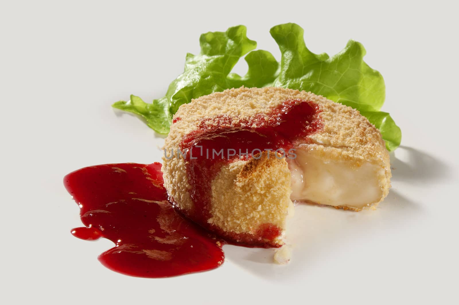 Baked camambert coated with breadcrumbs with lettuce and cowberries jam