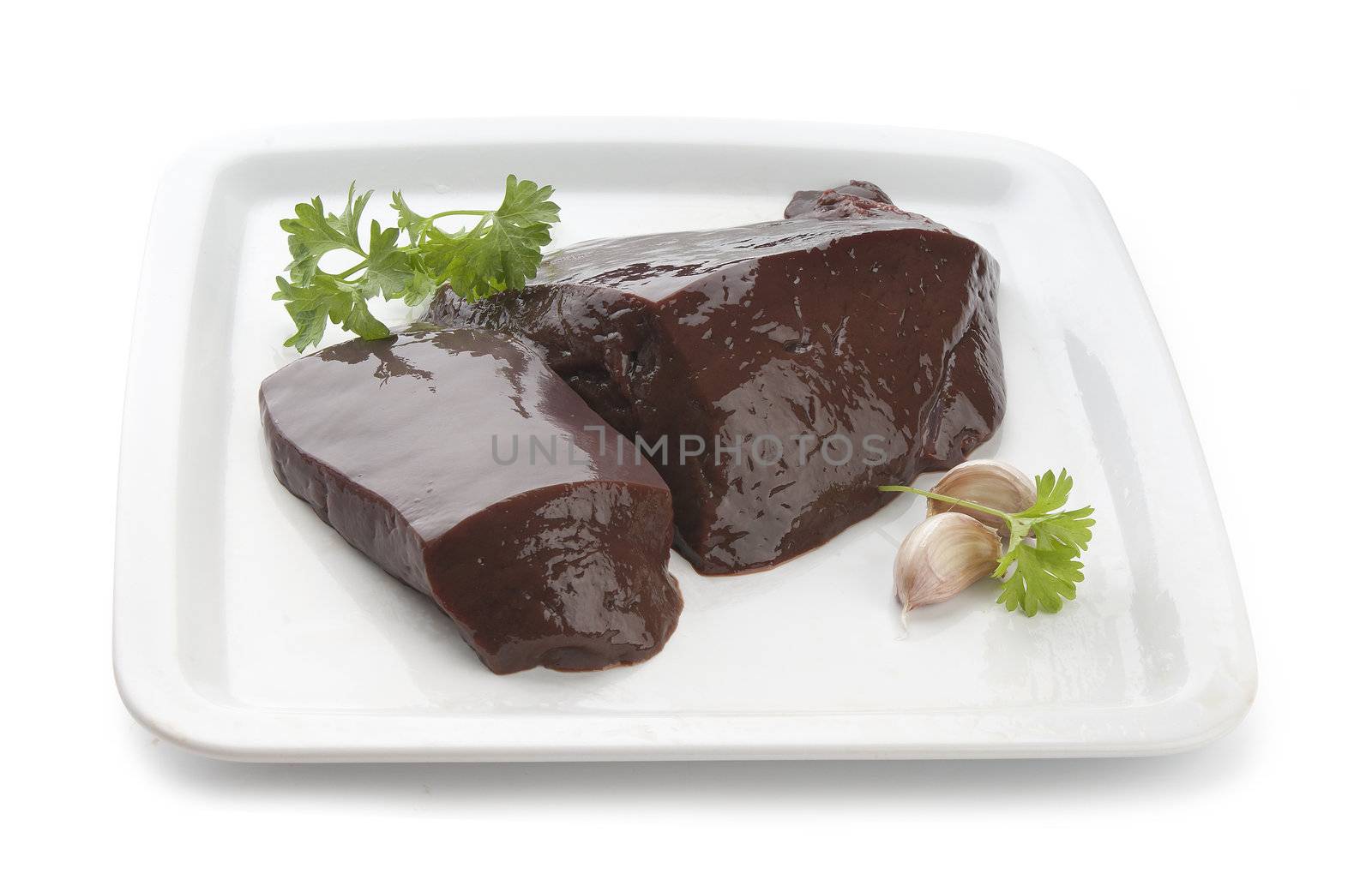 Two pieces of raw liver with fresh parsley on the white plate