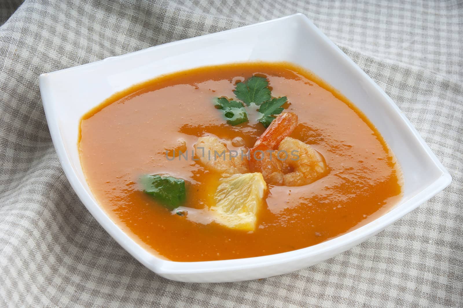 Tomato soup with shrimps, lemon and parsley in the white bowl