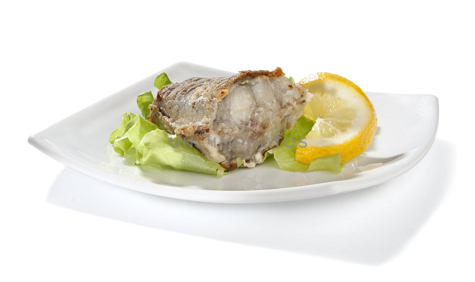Fried piece of cod with lettuce and lemon on the plate