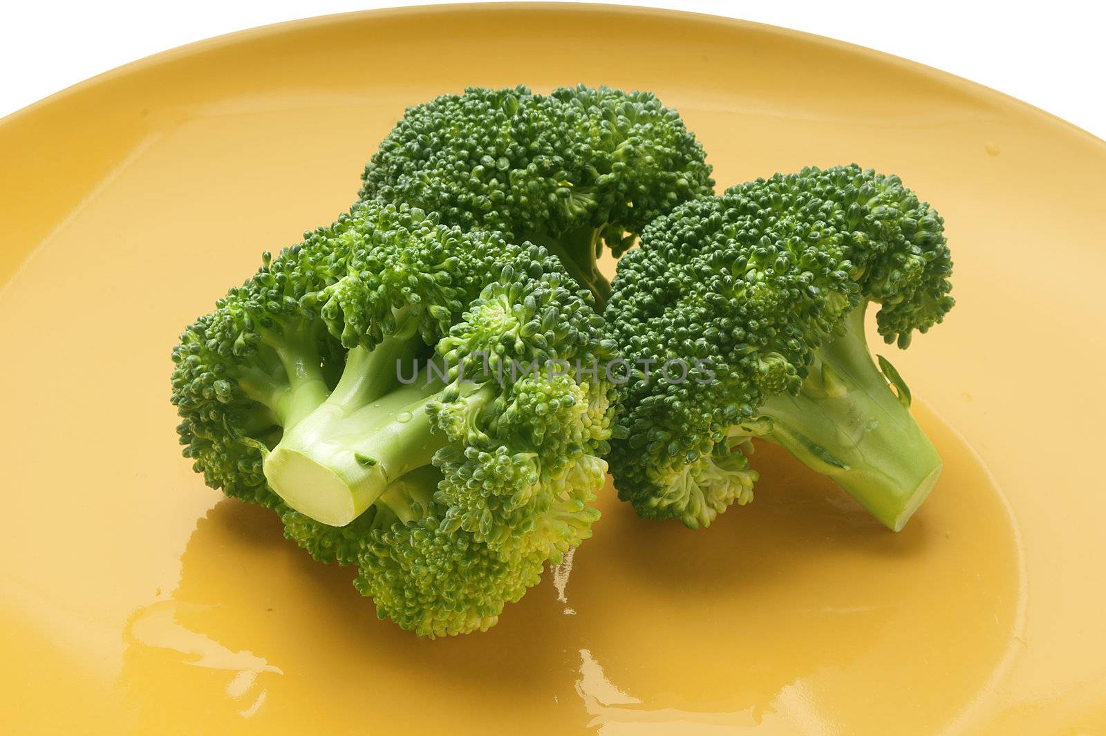 Some pieces of fresh green broccoli on the yellow plate