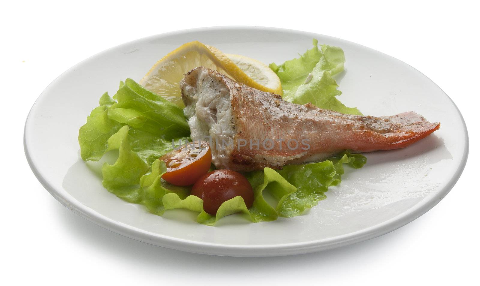 Baked rosefish with lettuce, tomato and lemon on the plate
