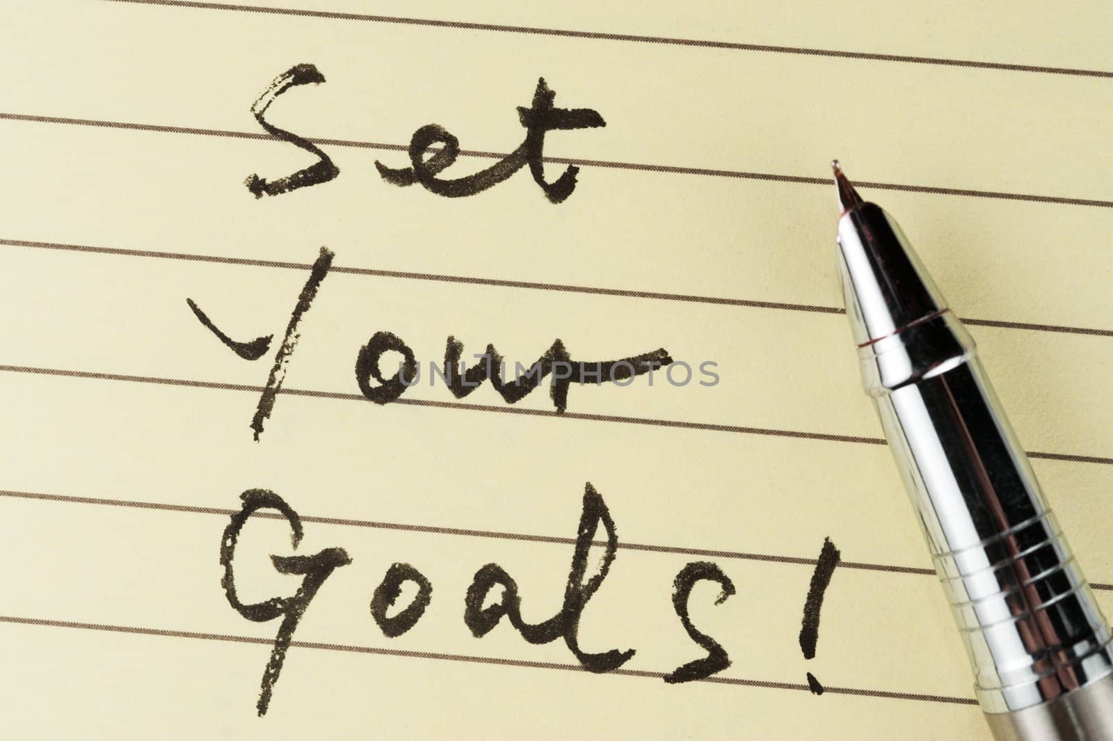 Set your goals words written on lined paper with a pen on it