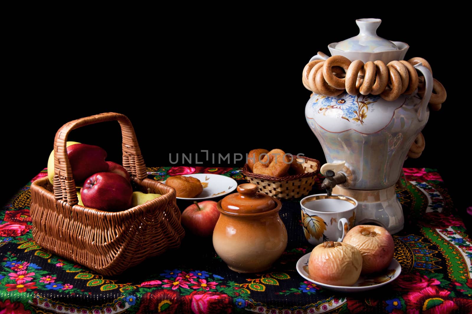 Samovar, bagels and apples on table over black isolated