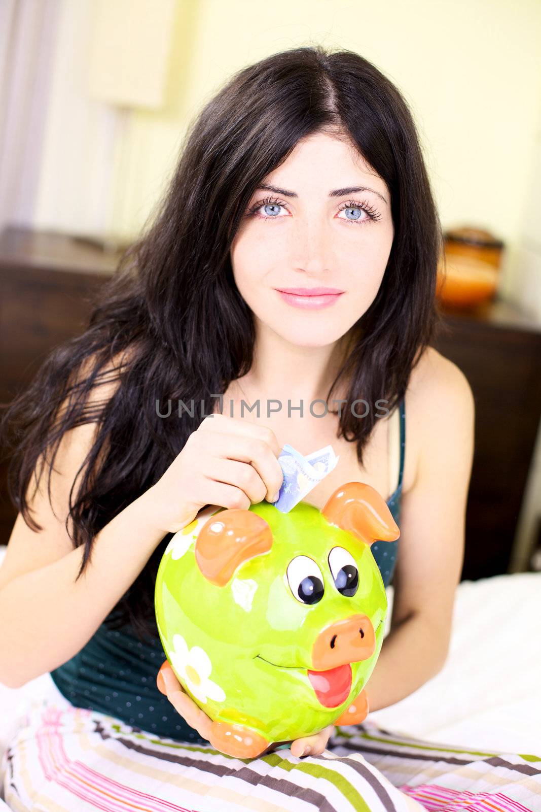 Happy woman putting money in piggy bank by fmarsicano
