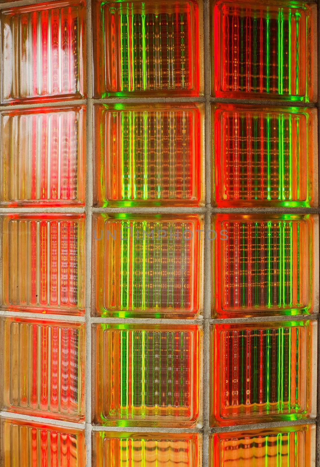 Curved glass brick wall lit from behind with red and green neon lights