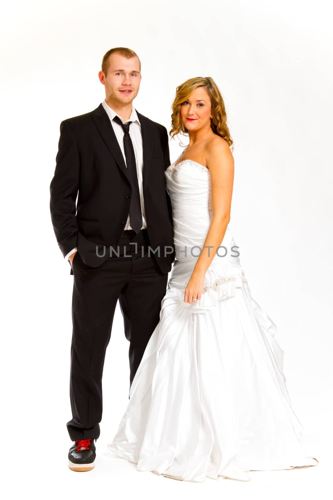 A beautiful bride and a handsome groom are isolated against a white background in the studio to create this bridal wedding portrait.