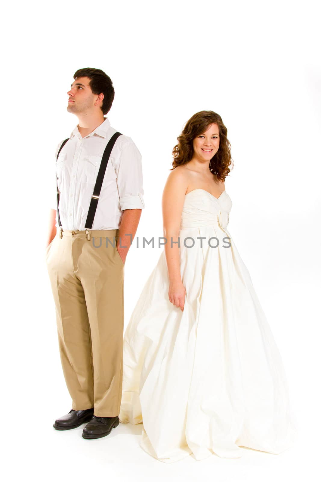 An attractive woman and her handsome husband wear their wedding attire in the studio agains an isolated white background.