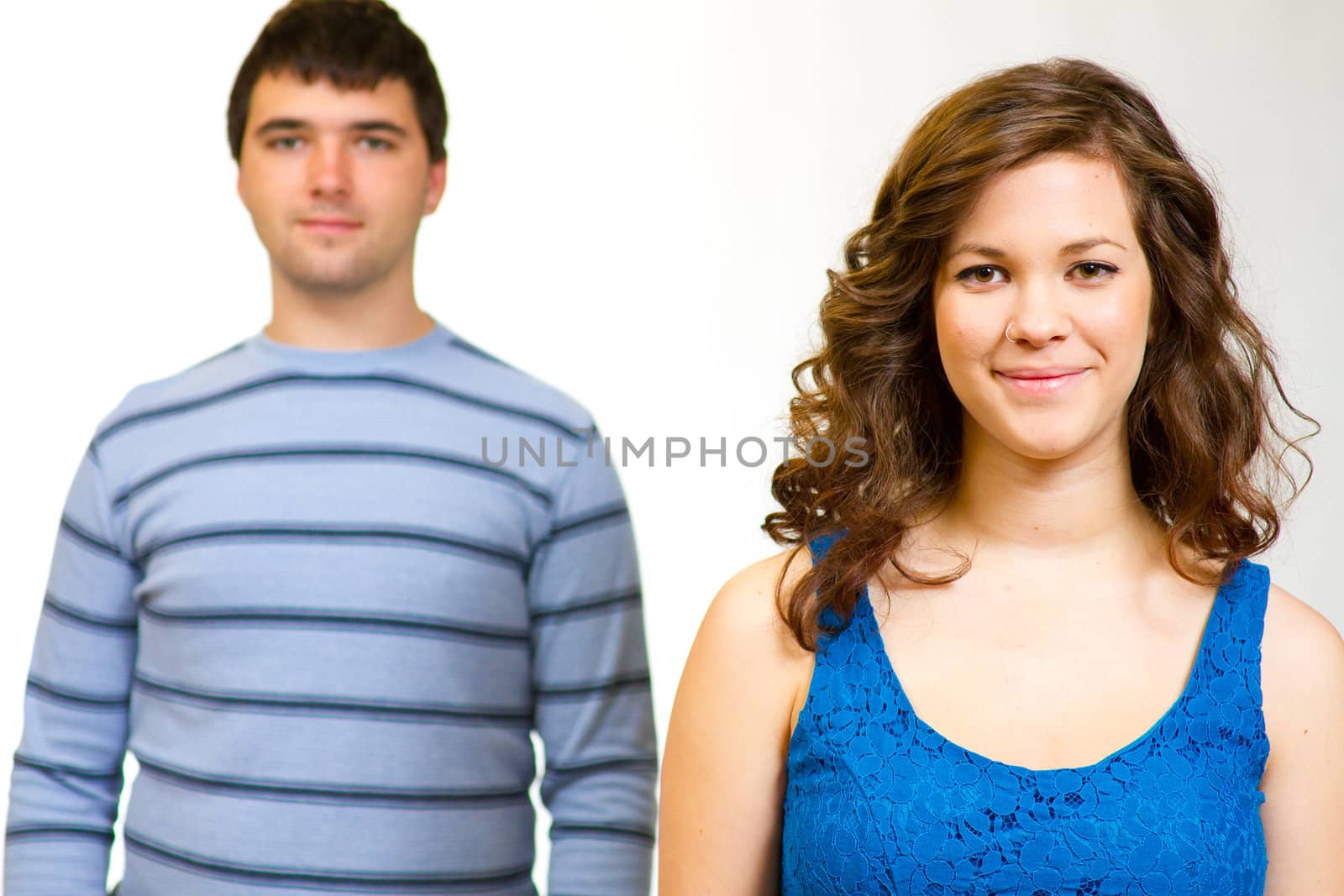 A white background studio shot of a young couple in blue fashionable stylish outfits.