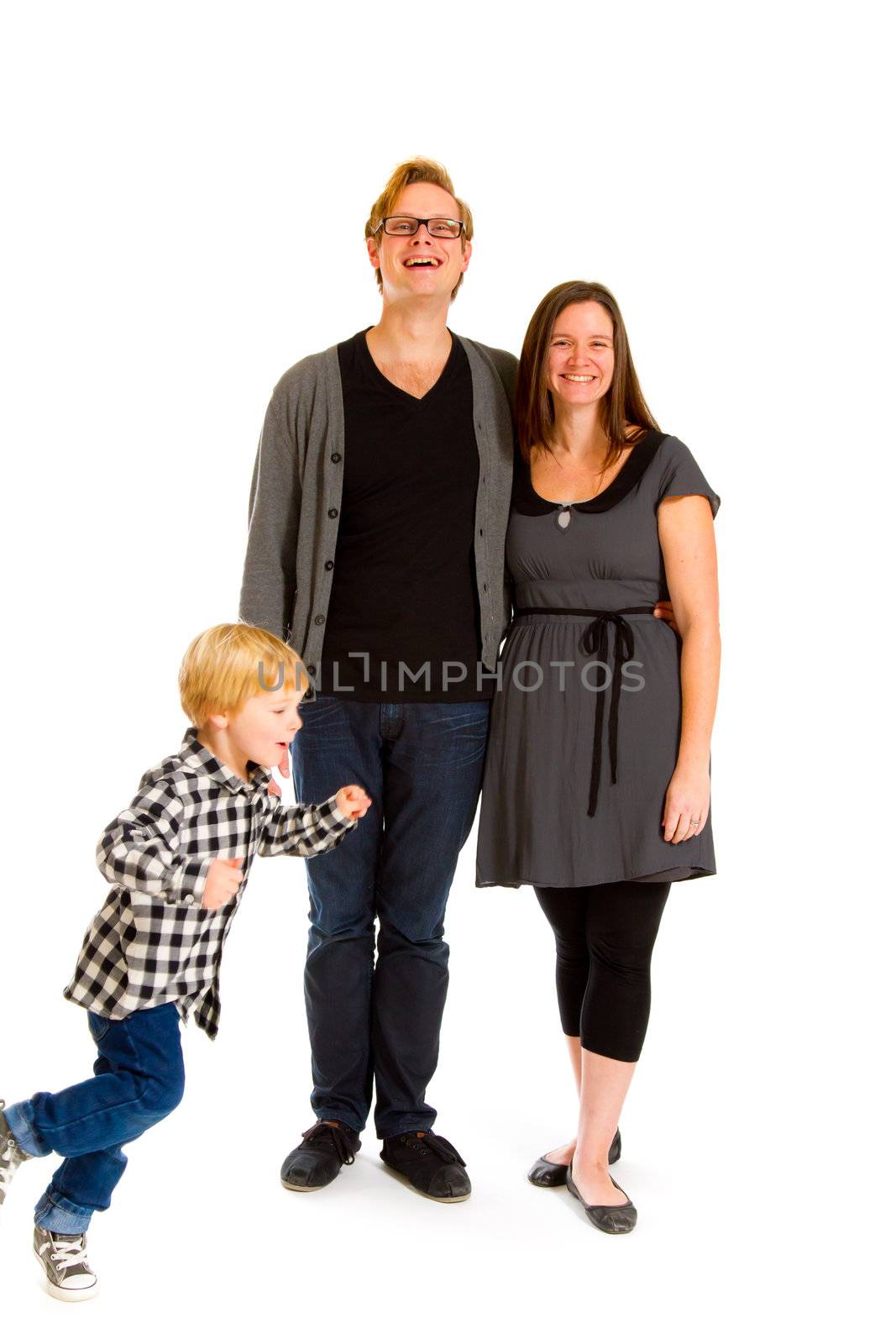 A couple stands there as their children run circles around them in the studio against an isolated white background.