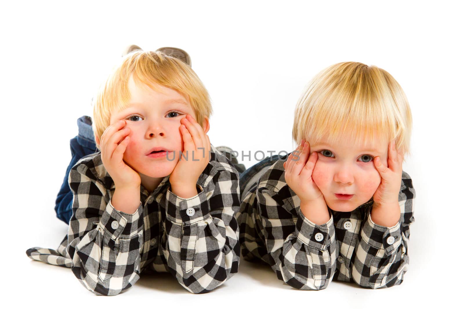 A boy and his sibling brother pose for this portrait in a studio against an isolated white background.