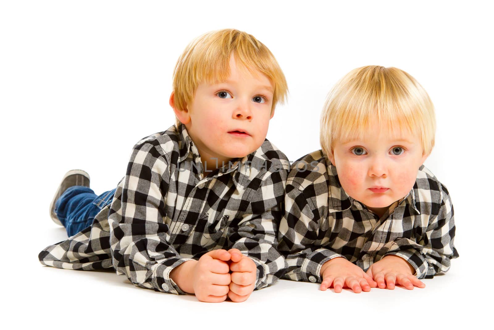 A boy and his sibling brother pose for this portrait in a studio against an isolated white background.