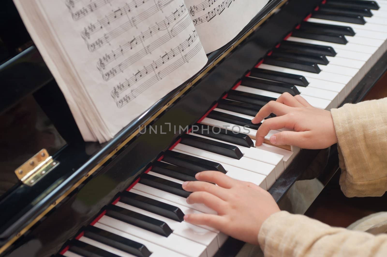 Hands of a little Asian kid learning to play piano