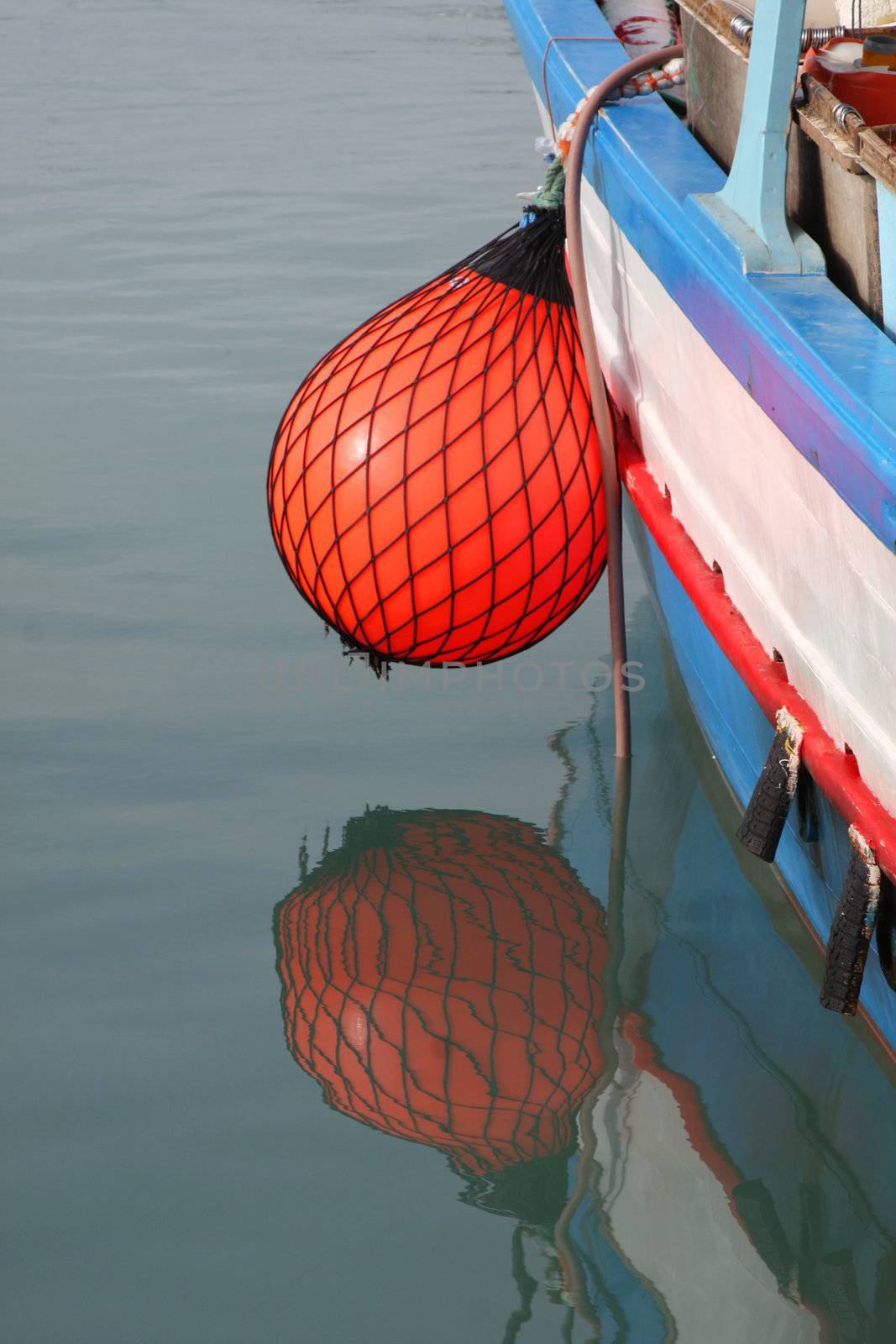 Bright red fender on side of a maltese fishing boat