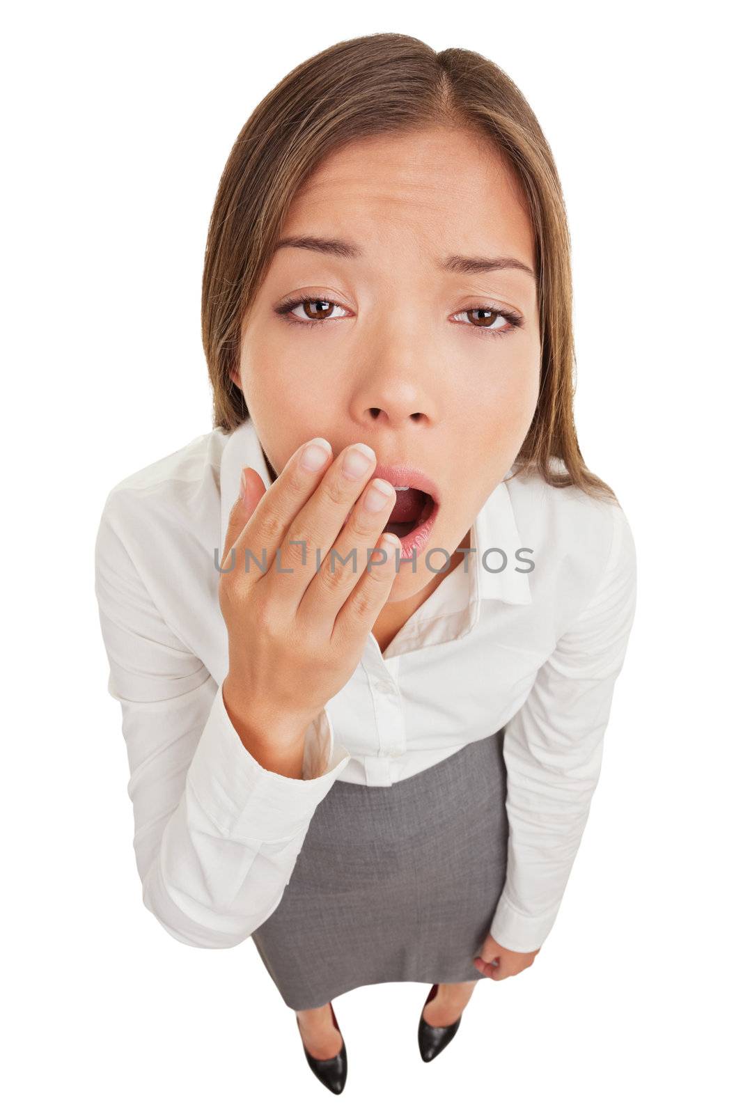 Exhausted or bored woman in yawn. Humorous high angle view of an exhausted or bored young woman yawning with her hand to her mouth and apathetic eyes, isolated on white background.