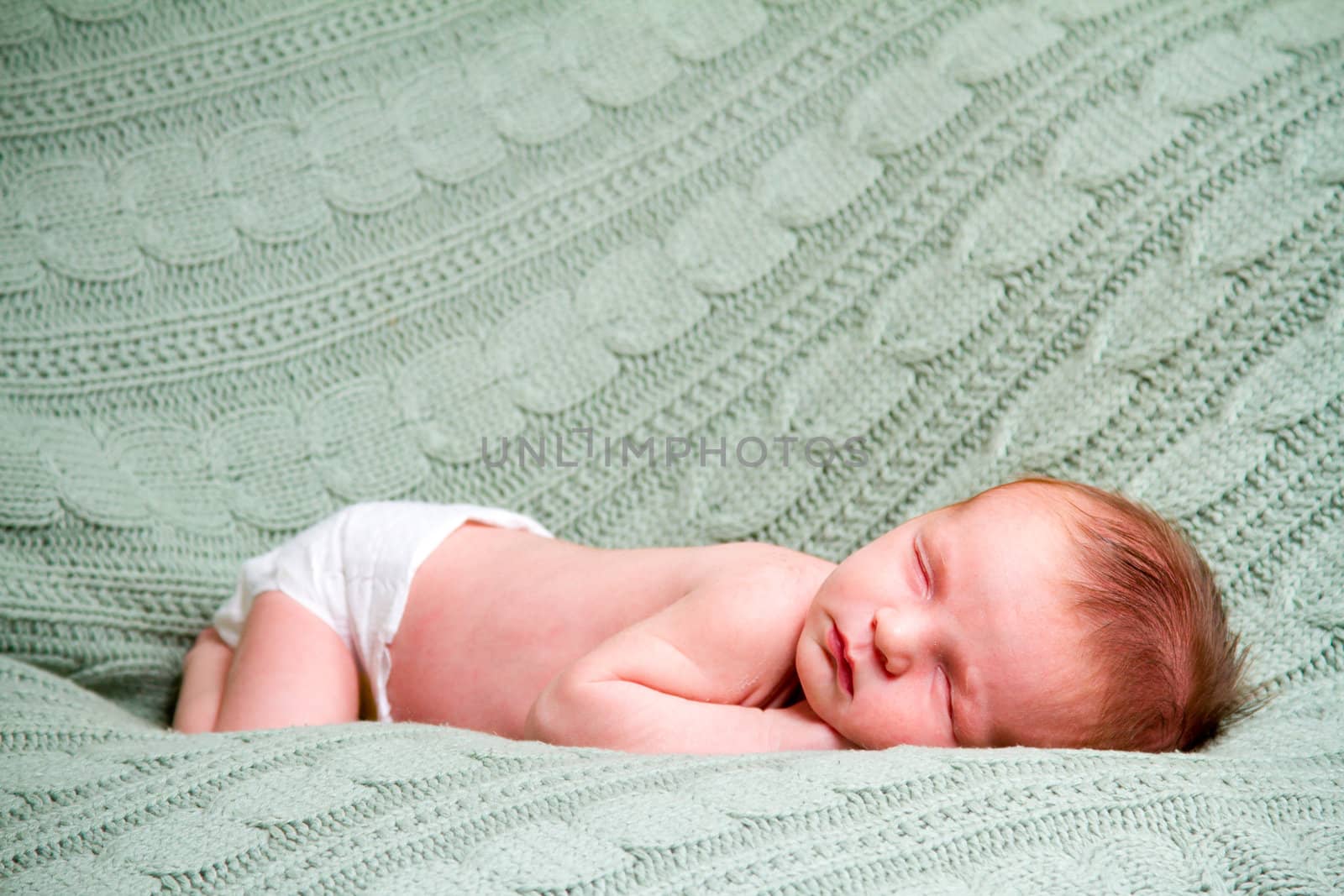 A baby boy sleeping on his side on a comfortable rug at his parents house.