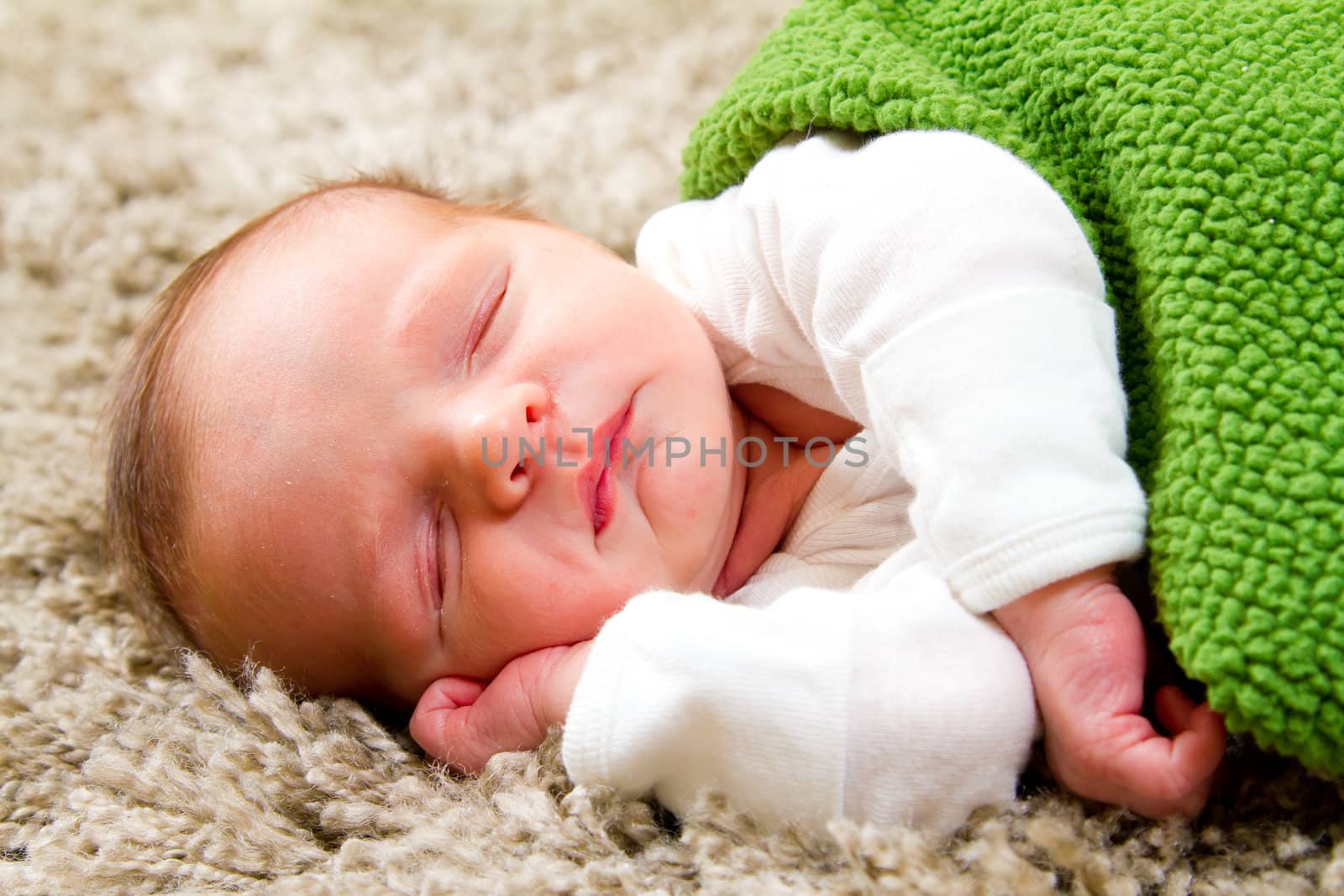 A baby boy sleeping on his side on a comfortable rug at his parents house.