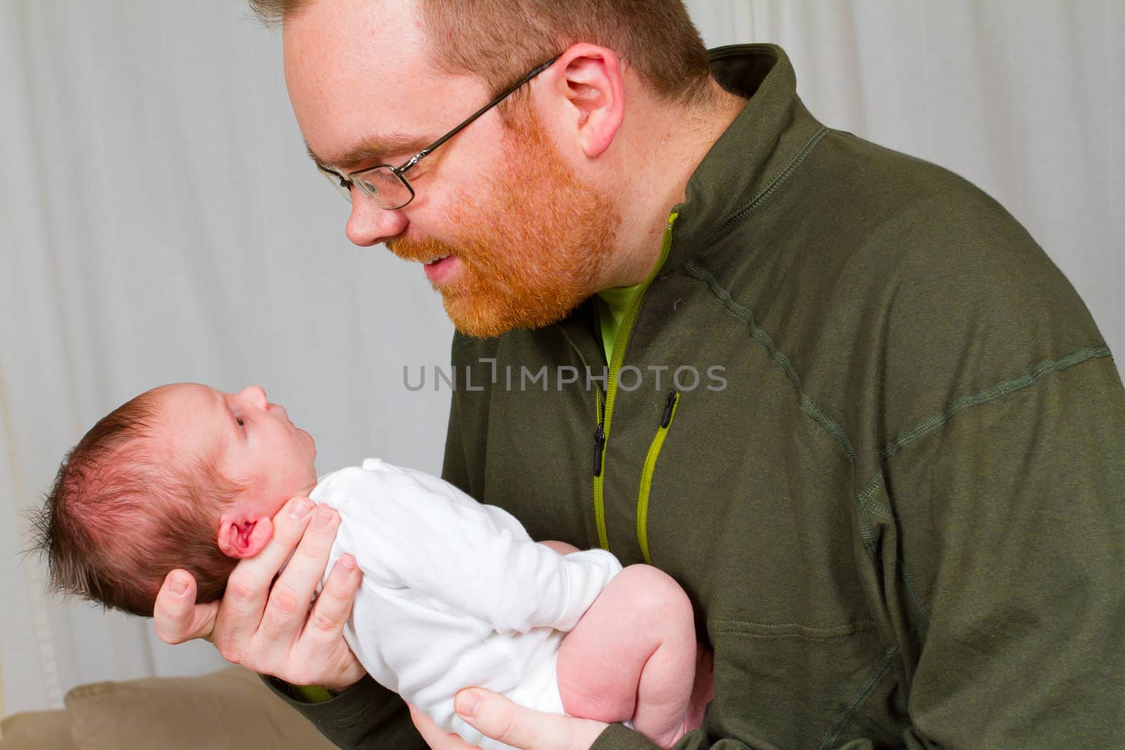 A father holds his newborn baby son in his arms.