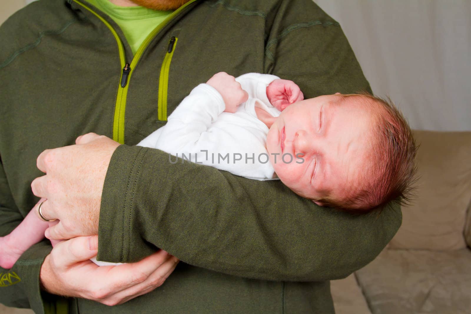 A father holds his newborn baby son in his arms.