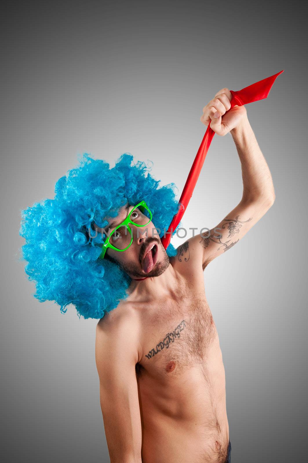 man with blue wig who choking with tie on gray background
