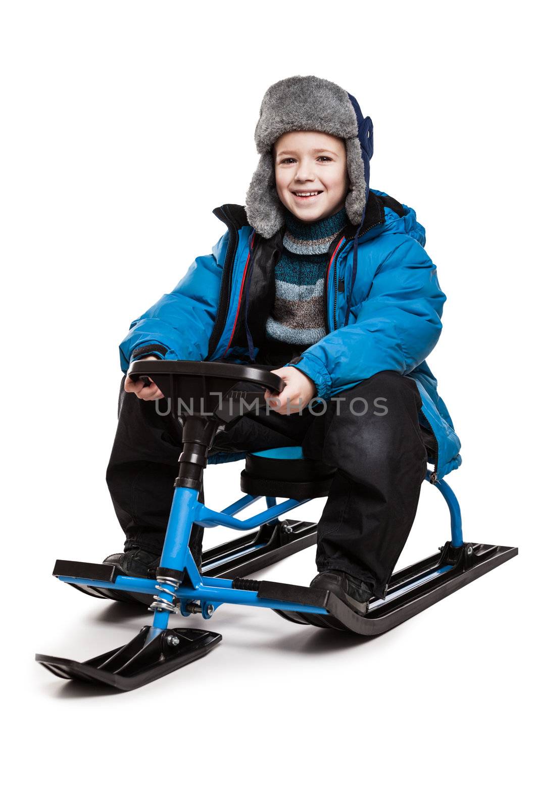 Little smiling child boy sitting on snow scooter or snowmobile toy white isolated