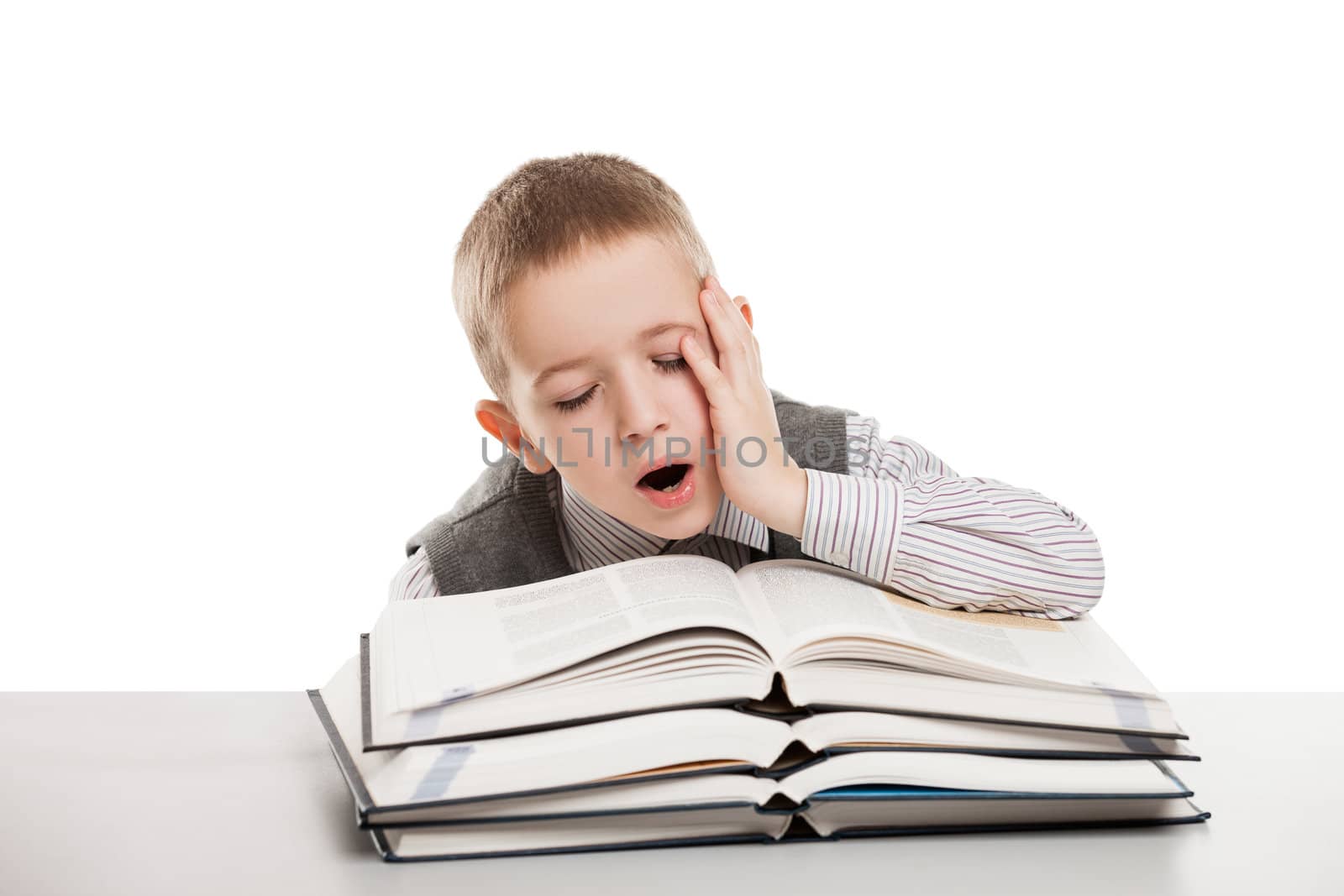 Tired child boy yawning on education reading books at school desk