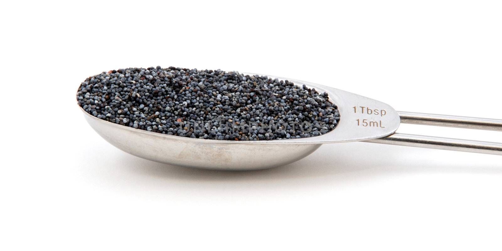 Poppy seeds measured in a metal tablespoon, isolated on a white background