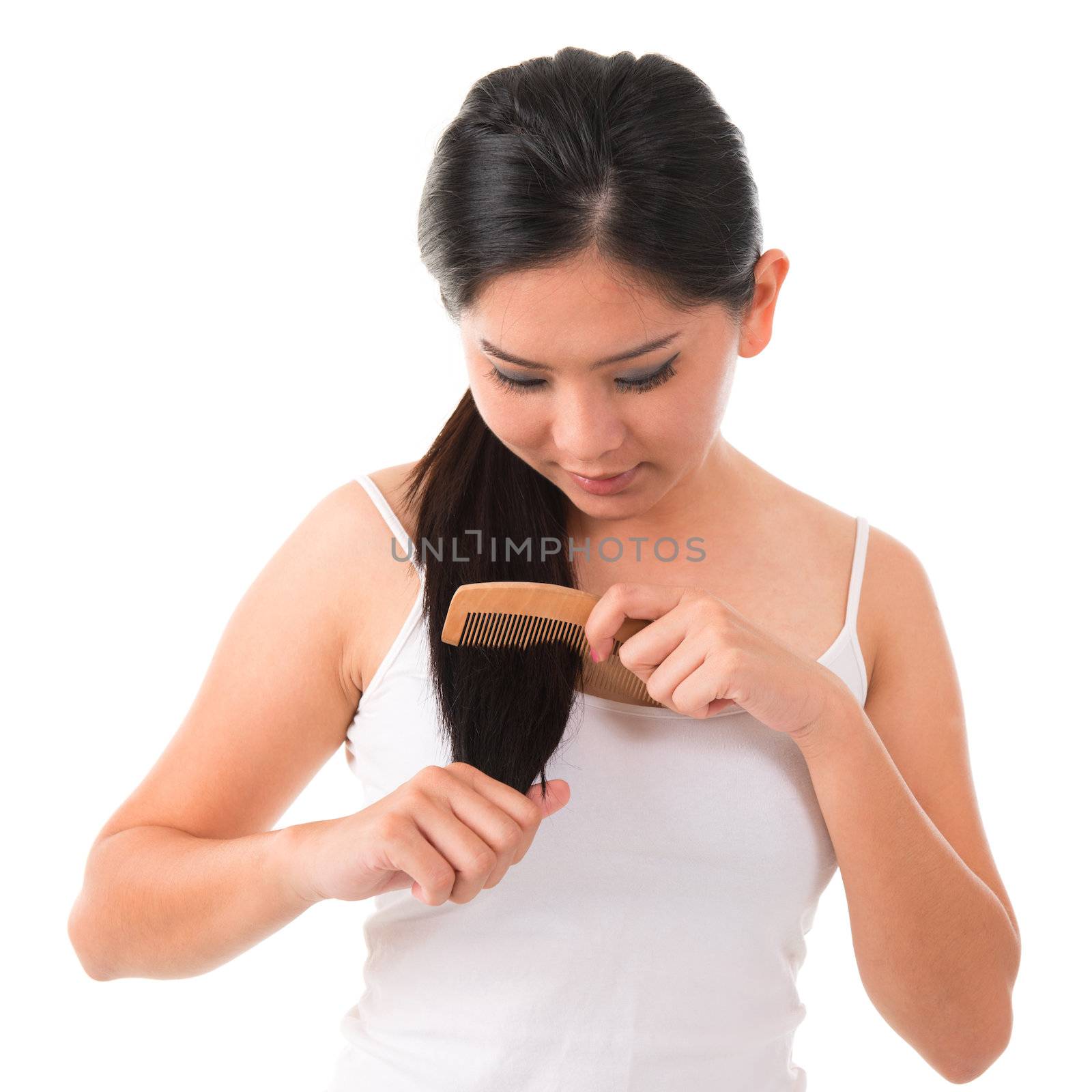 Young Asian female combing her hair over white background