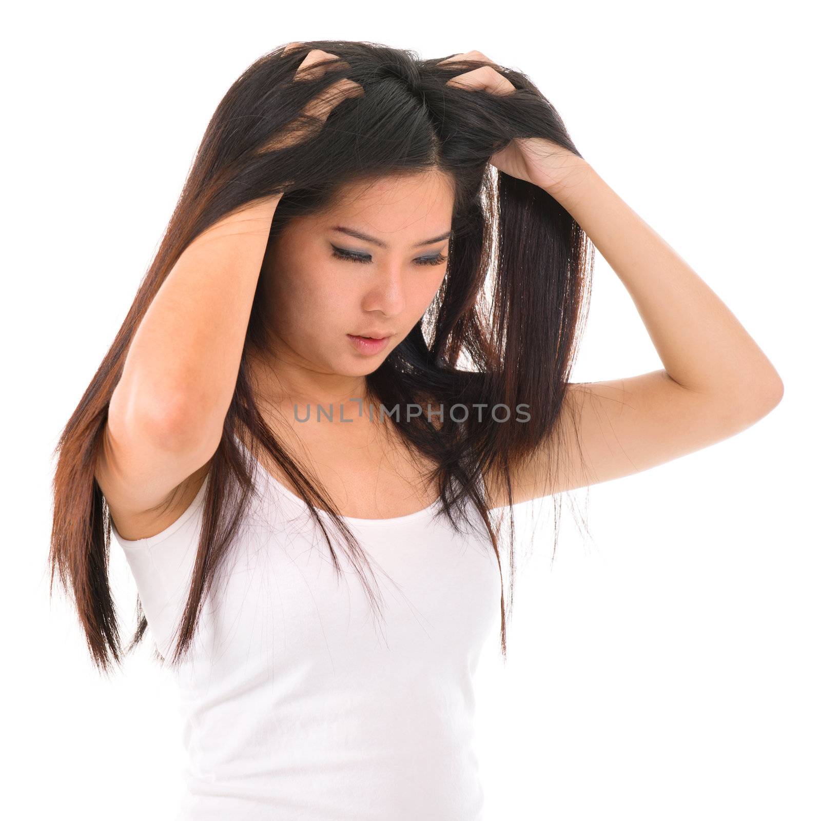 Young Asian girl scratches her hair on white background