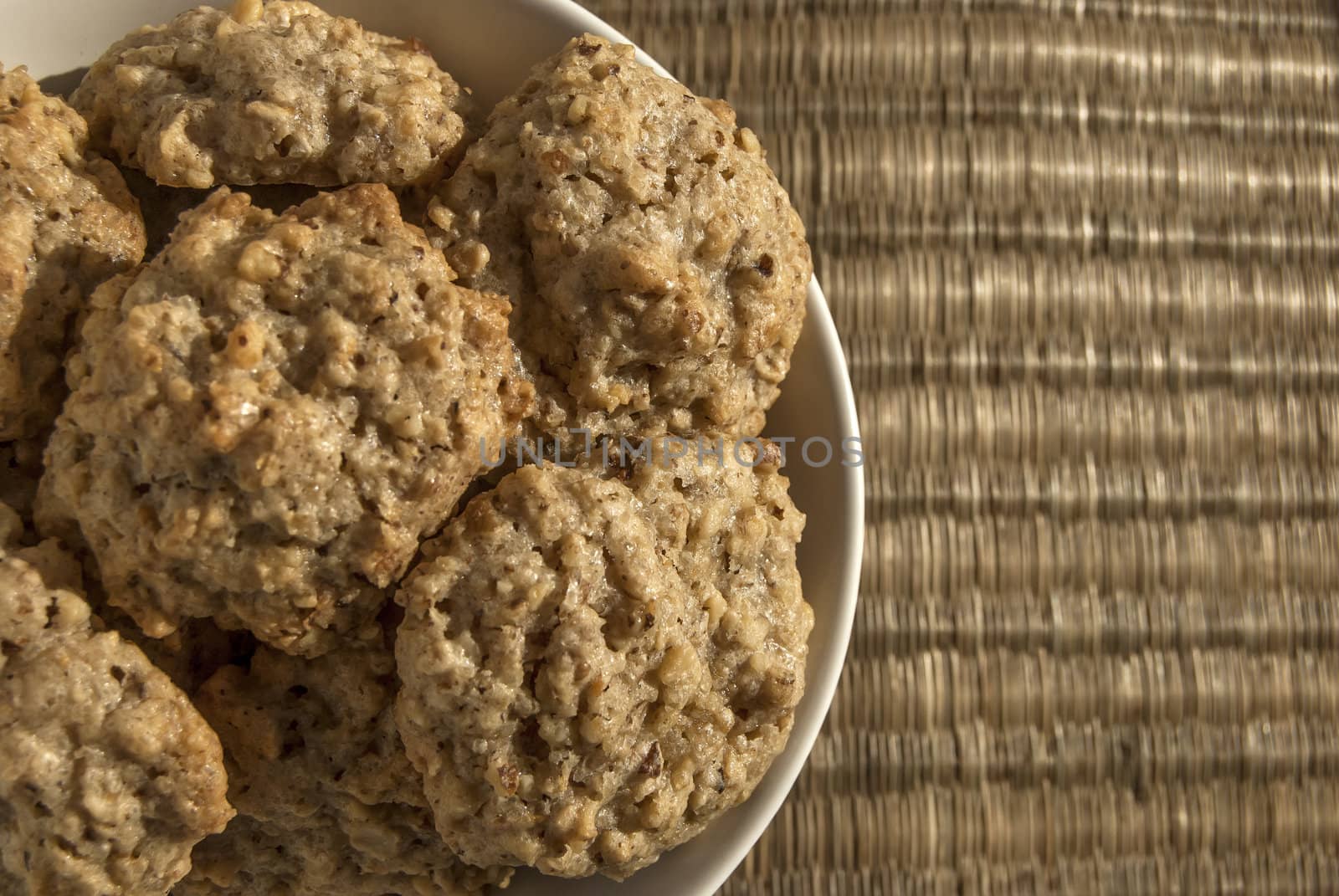 Homemade oatmeal cookies in bowl on reed mat closeup